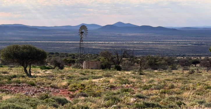 Rural landscape with windmill, water tank, and distant mountains